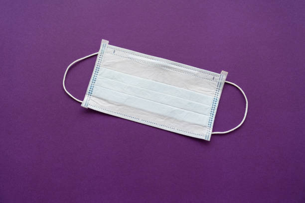 istock a disposable medical mask on a purple background. 1216561659