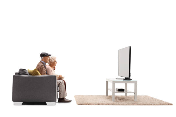 ソファに座ってテレビを見ている先輩男女のプロフィールショット - couple indoors studio shot horizontal ストックフォトと画像