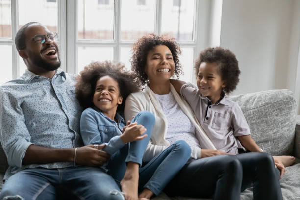 istock African couple with kids enjoy communication laughing resting on sofa 1216561990
