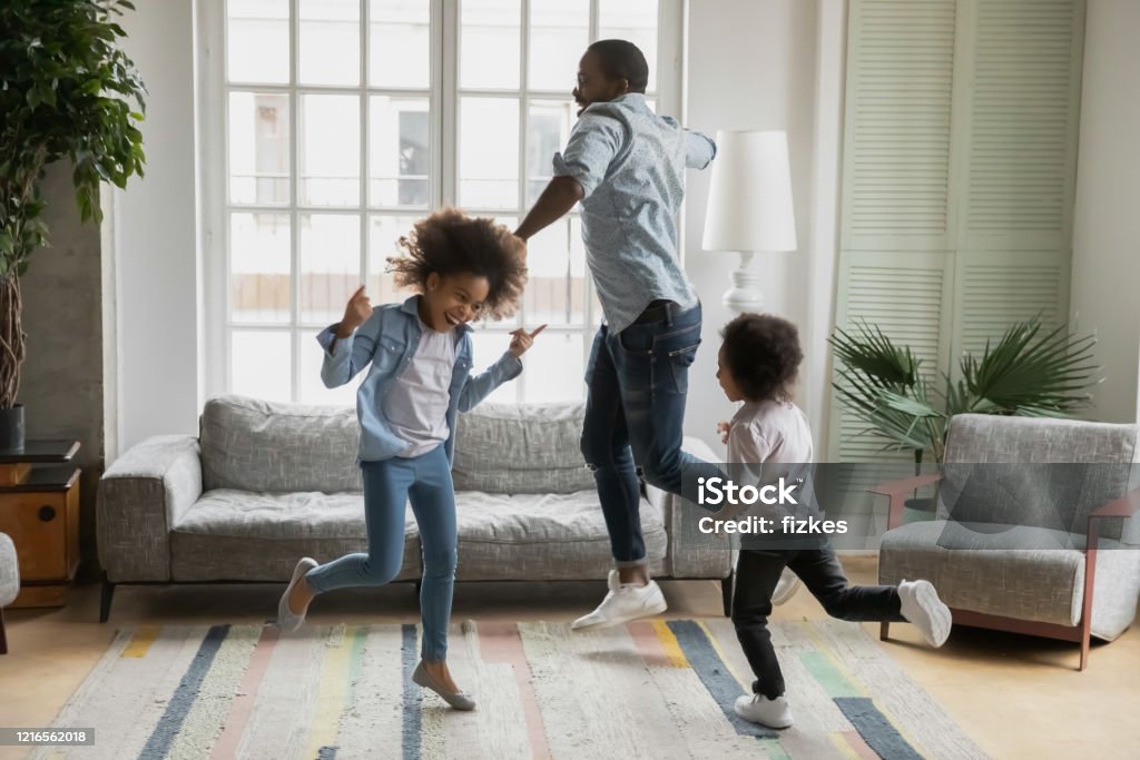 Padre africano hijo e hija escuchando música bailando en casa - Foto de stock de Familia libre de derechos