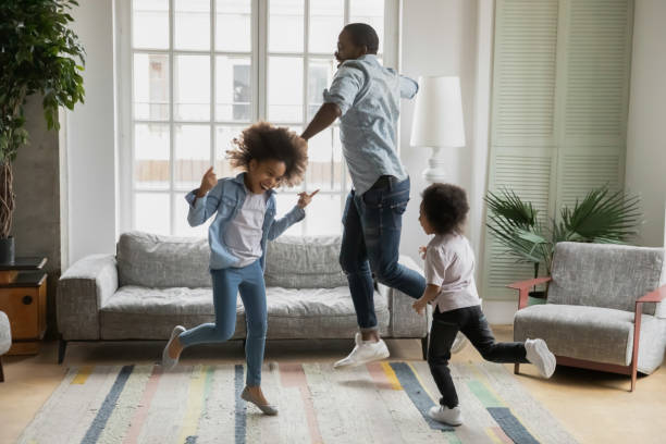 padre africano hijo e hija escuchando música bailando en casa - saltar actividad física fotos fotografías e imágenes de stock