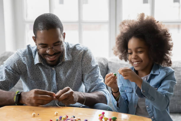 istock African dad and little daughter making bracelet using colorful beads 1216562033