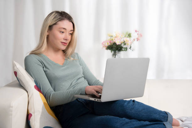 istock A typical Millennial Generation blond young woman, working on her laptop computer and looking confident and happy. The photo is to represent working from home or studying for examination at home. She is wearing a green shirt and blue denim. 1216562144