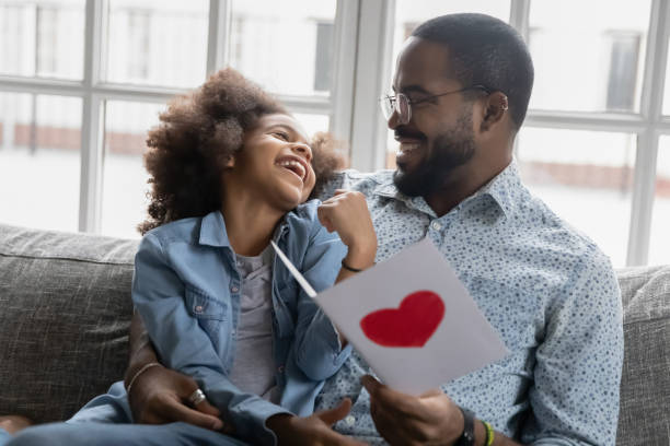 African daughter presented postcard to daddy reading wishes feels happy