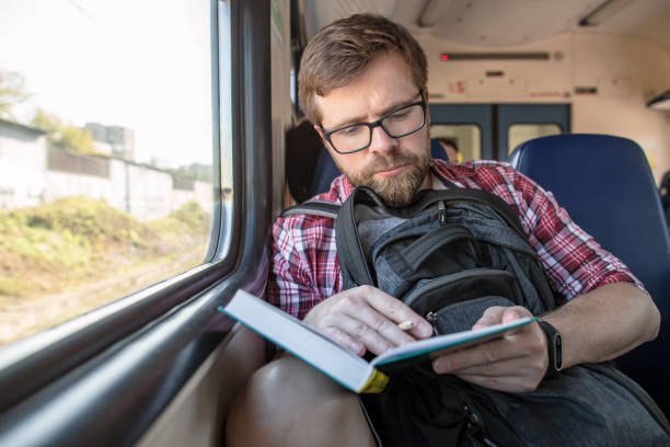 istock Focused bearded man riding in a train, reading a book and making notes with a pencil. 1216563493