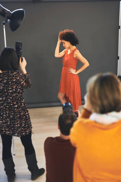 istock Three attendees  standing in studio and taking photos of beautiful mixed race female model. 1216565739
