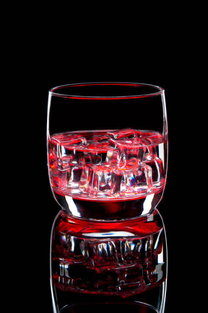 istock Water with ice in a glass with a red glow. Refreshing cocktail on a red background 1216566171