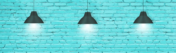 wiszące lampy wiszące przed turkusową malowanym murem z cegły. nowoczesne industrialne tło wnętrza - metallic wall brick glowing zdjęcia i obrazy z banku zdjęć