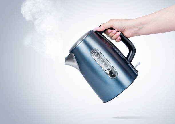 istock Female hand holds an electric kettle, on light background. File contains a path to isolation. 1216569941