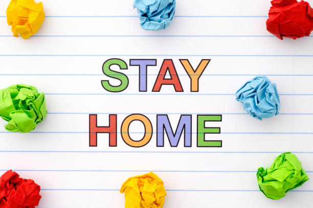 istock Phrase Stay Home on notebook sheet with some colorful crumpled paper balls around it 1216570212