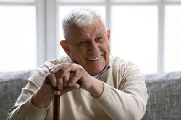istock Positive old grandfather holding walking stick resting on couch 1216570461