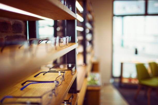 gafas en una tienda de óptica ordenadas en una fila en el estante - instrumento óptico fotografías e imágenes de stock