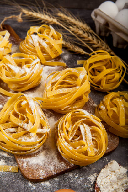 istock Pasta tagliatelle and ingredients for cooking on dark background, top view. 1216573895