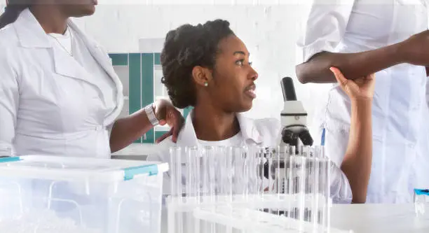 Female African medical students, young graduates or doctors discuss ongoing project. Team working together in test lab. Testing samples from patients with coronavirus pneumonia or biopsy for cancer.