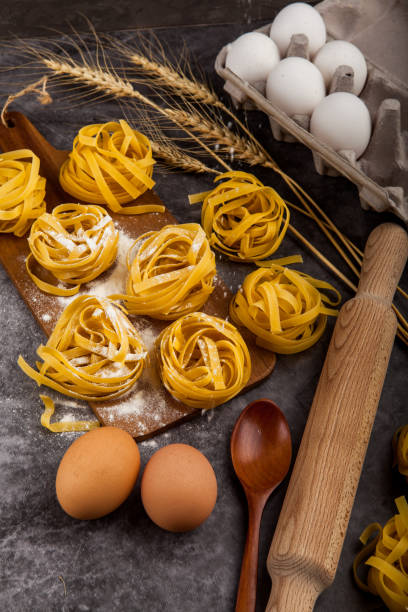 istock Pasta tagliatelle and ingredients for cooking on dark background, top view. 1216573993