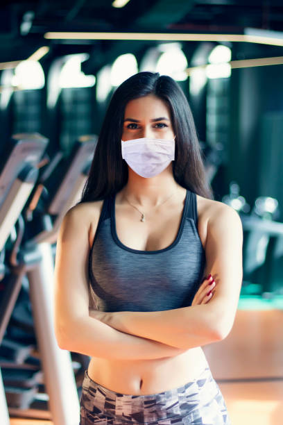 若いフィットネススポーツの女性が走っていると彼女は保護ダストと汚染と保護インフルエンザウイルス、ジムコロナウイルスの概念のためのマスクを着用しています。 - toxic substance dirt pollution scientific experiment ストックフォトと画像