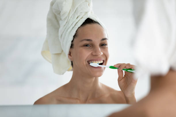 istock After shower woman looking in mirror and brushing her teeth 1216575401