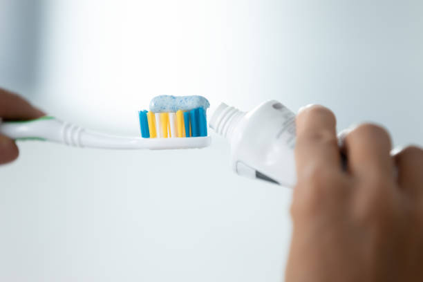 immagine ravvicinata le mani femminili stringono il dentifricio sullo spazzolino da denti - healthy lifestyle toothbrush caucasian one person foto e immagini stock