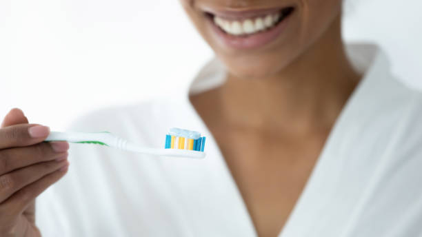 istock Closeup image african woman holding toothbrush with toothpaste 1216575477