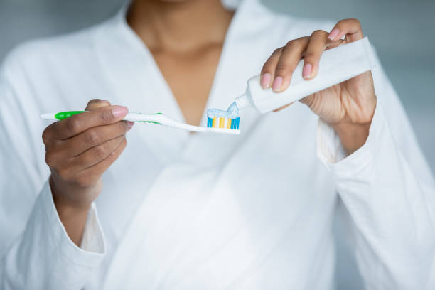 クローズアップビュー女性の手は歯ブラシでチューブから歯磨き粉を適用します - brushing teeth human teeth women cleaning ストックフォトと画像