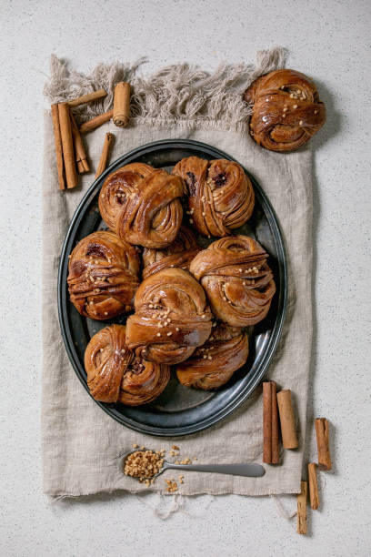 Swedish cinnamon sweet buns Traditional Swedish cinnamon sweet buns Kanelbulle on vintage tray, cinnamon sticks on linen cloth over white texture background. Flat lay, space. kanelbulle stock pictures, royalty-free photos & images