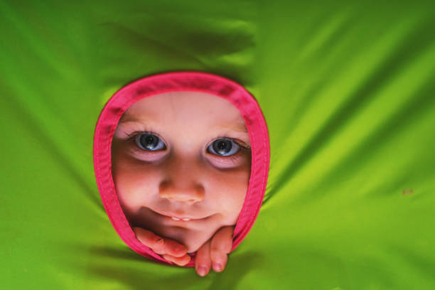 A three year old girl has fun inside a play tent.