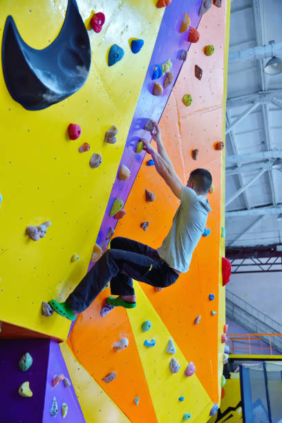 istock Young man climbing up on practice wall in gym. 1216579820