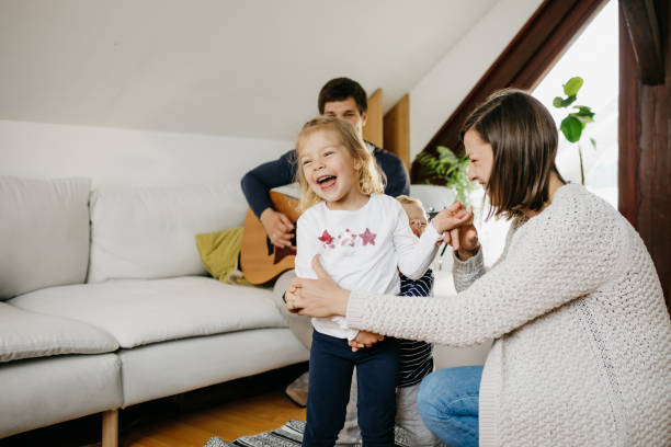 Young family dancing together Two little kids and their mother are dancing in a living room while father is playing the guitar. They are casually dressed and it is daytime. baby boy dancing with his mommy stock pictures, royalty-free photos & images
