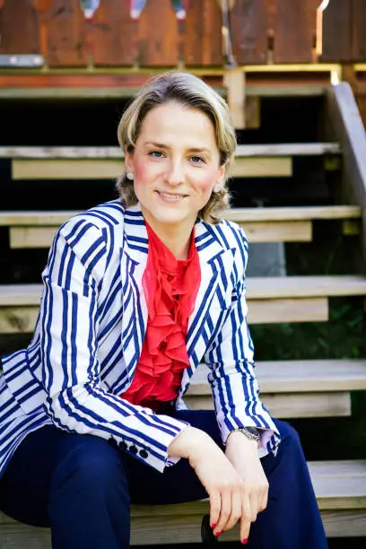 June 30, 2013 - Norway: pretty attractive blond young woman - a businesswoman - sitting, smiling on a country house steps, wearing beautiful clothes