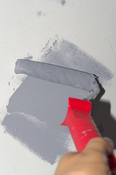 istock Human hand holding paint roller at gray stroke on white wall 1216585389