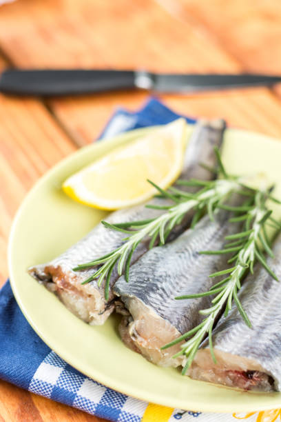 Flat lay green plate with hake fish and rosemary and lemon Flat lay green plate with hake fish and rosemary and lemon. merluza stock pictures, royalty-free photos & images