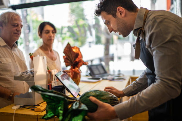 owner selling easter egg for a senior couple in a store - retail occupation cash register retail selling imagens e fotografias de stock