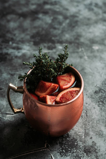 istock Red oranges cocktail in copper mug (variation of Moscow mule) on the wooden background 1216591127