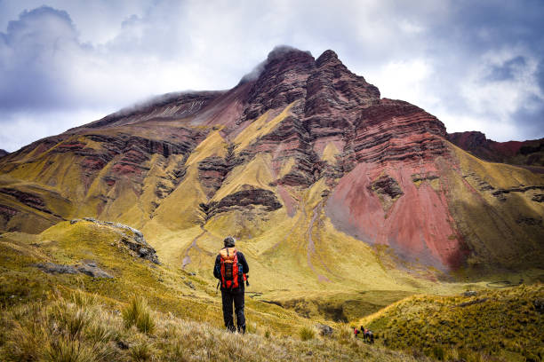 A hiker walks among dramatic mountain landscapes on the Ancascocha Trek to Machu Picchu in the Peruvian Andes. Cusco, Peru.