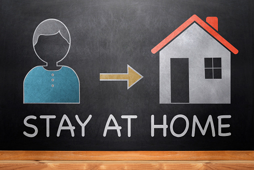 Stay Home text, person And House icon, direction arrow on black chalkboard