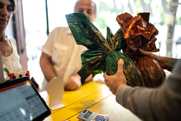 owner selling easter egg for a senior couple in a store - retail occupation cash register retail selling imagens e fotografias de stock