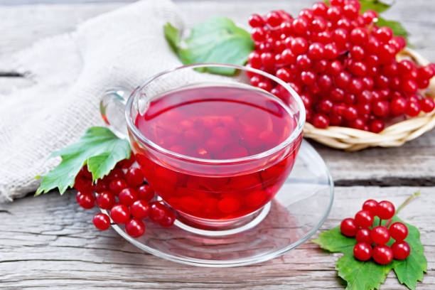 istock Tea from viburnum in cup with berries on old board 1216595356