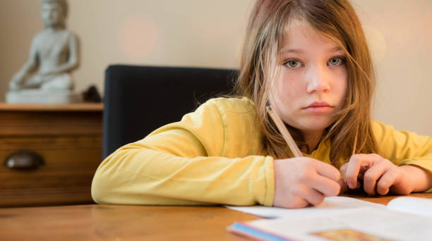 istock cute little girl doing her school work in the dining room 1216596620