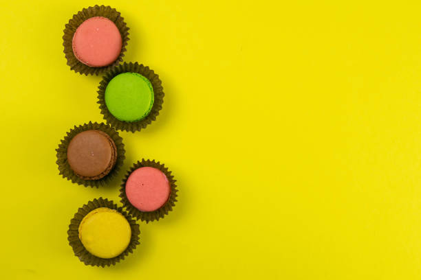 istock Colorful macaroons in a beautiful brown wrapper stand on a yellow background 1216596671