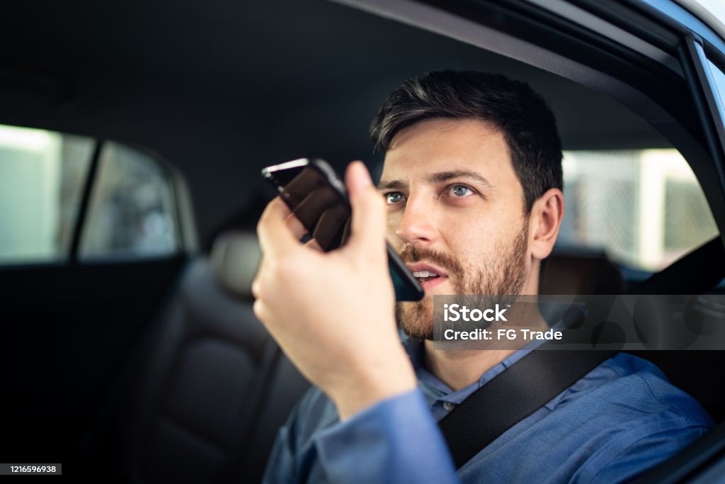 Businessman talking on mobile phone at passenger seat inside a car Virtual Assistant Stock Photo