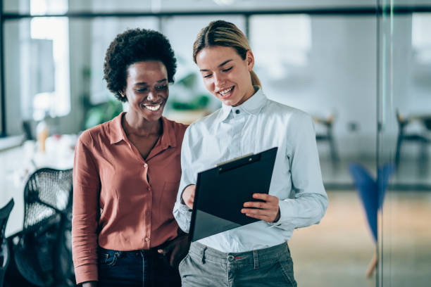 Confident female business team. Shot of two businesspeople having a discussion in modern office. Two young diverse businesswomen discuss important documentation and sharing ideas. african descent analyzing business white stock pictures, royalty-free photos & images