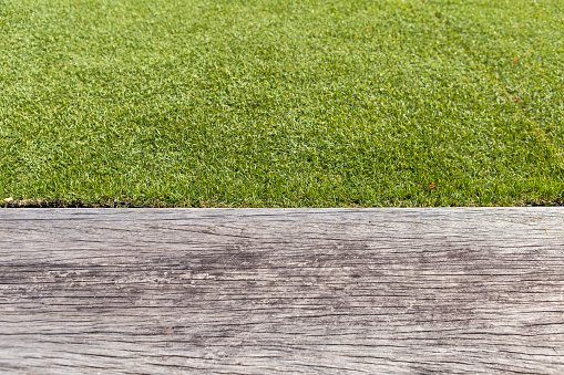 Green grass with space on grey old wood floor background, outdoor daylight