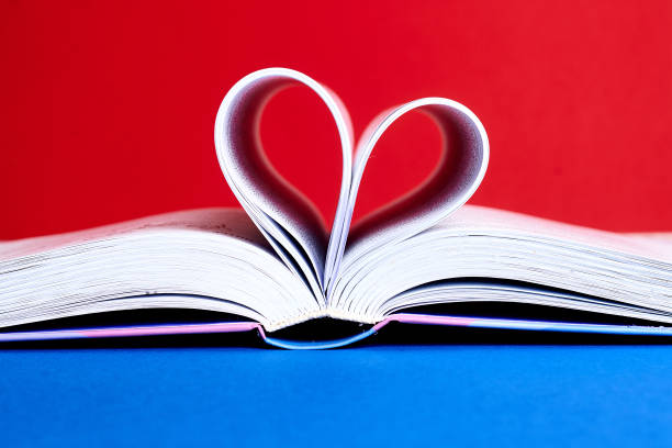 istock An open book with a folded heart of pages on a red and blue background. 1216599740