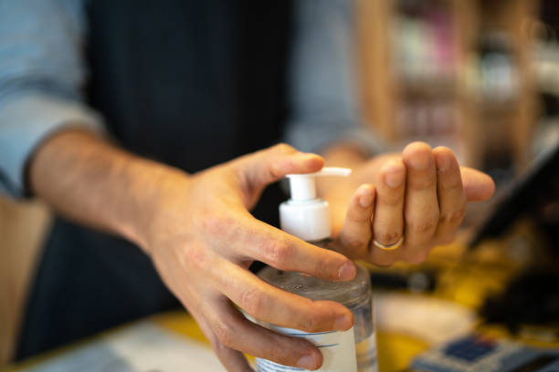 entrepreneur utilisant le gel d’alcool pour nettoyer et laver la main à sa petite entreprise - supermarket sales clerk retail cashier photos et images de collection