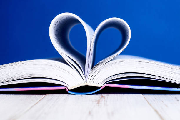 istock An open book with a rolled heart of pages on a blue background. 1216600037