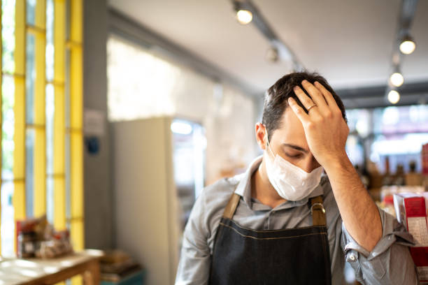Worried owner with face mask at his small business Worried owner with face mask at his small business pandemic illness stock pictures, royalty-free photos & images