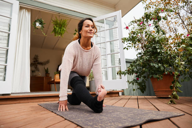 mature woman practicing yoga alone on her deck - the splits ethnic women exercising imagens e fotografias de stock