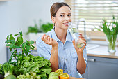 Healthy adult woman with green food in the kitchen