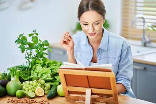 Picture of healthy adult woman with green food in the kitchen