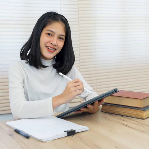 istock Young cheerful Asian student female university student studying in self study room in the university library to do her assignment and prepare for examination. 1216604782